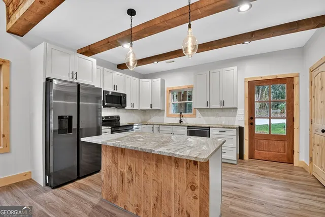 a kitchen with stainless steel appliances granite countertop a refrigerator a sink dishwasher a stove and a refrigerator with wooden floor