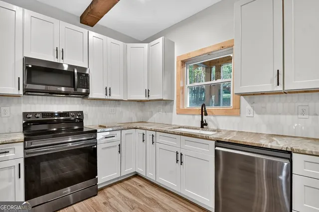a kitchen with cabinets stainless steel appliances a sink and a window