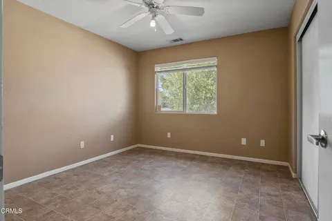 en empty room with windows and chandelier fan