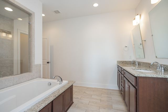 a bathroom with a granite countertop sink and a bathtub