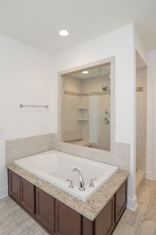 a bathroom with a granite countertop tub sink and mirror