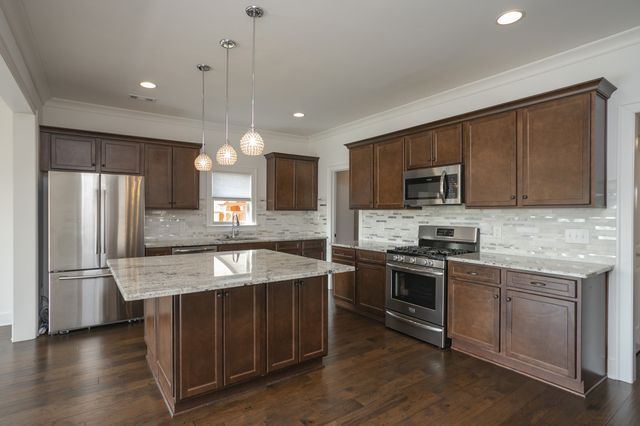 a kitchen with stainless steel appliances granite countertop a sink stove microwave and refrigerator