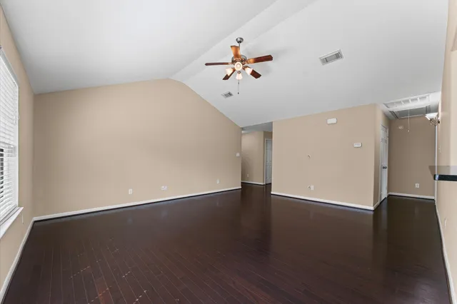 an empty room with wooden floor and windows