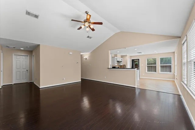 a view of an empty room with wooden floor and a window