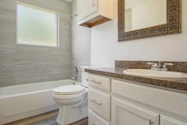 a bathroom with a granite countertop sink a toilet and bathtub