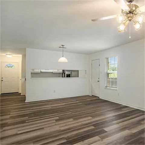 an empty room with wooden floor and chandelier fan