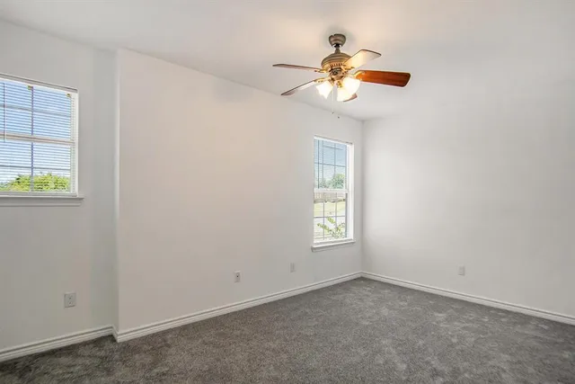 an empty room with windows and chandelier fan