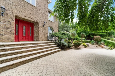 a view of a house with potted plants and large tree