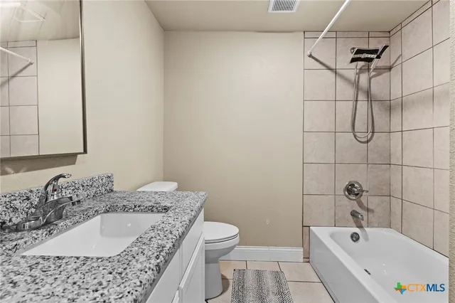 a bathroom with a granite countertop sink a toilet and bathtub