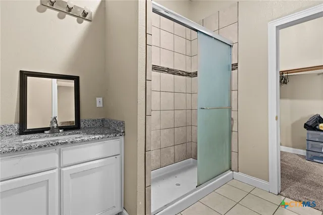 a bathroom with a granite countertop sink a mirror and shower