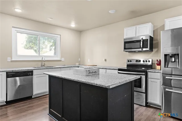 a kitchen with stainless steel appliances granite countertop a sink stove microwave and refrigerator
