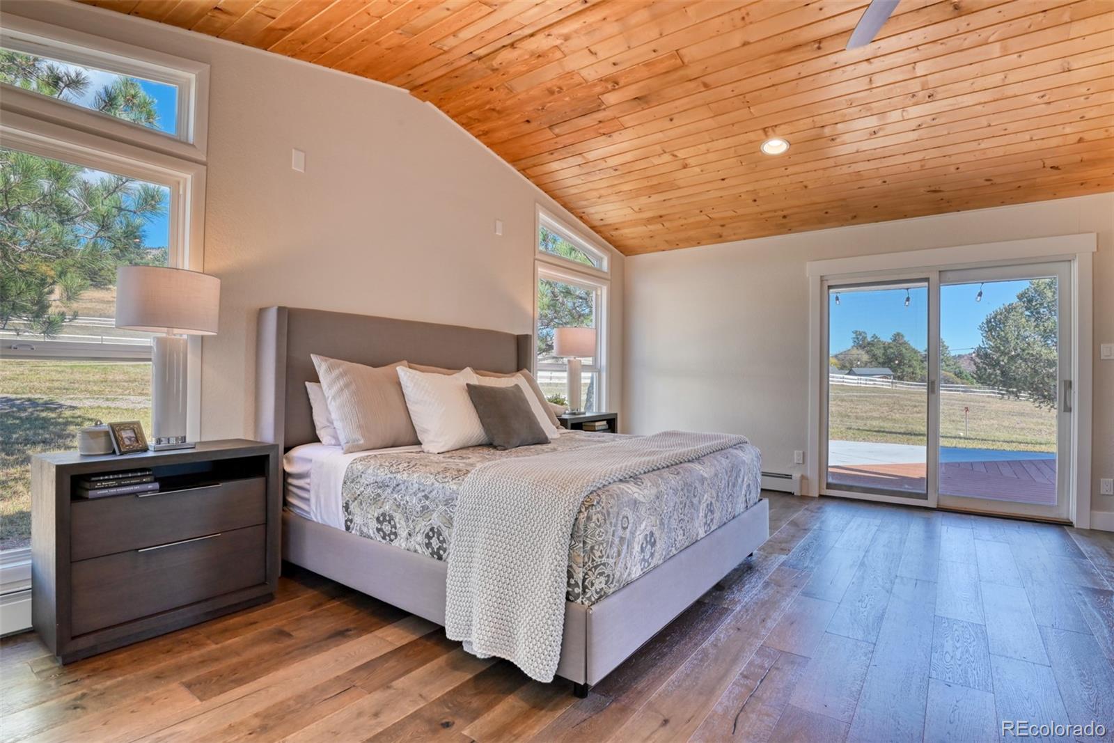 850 West Fox Farm Road Larkspur, CO 80118 - Photo 33 of 50 a bedroom with a bed and large windows
