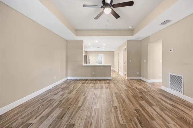 a view of empty room with wooden floor and fan