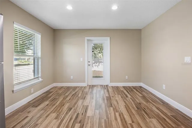 a view of an empty room with wooden floor and a window