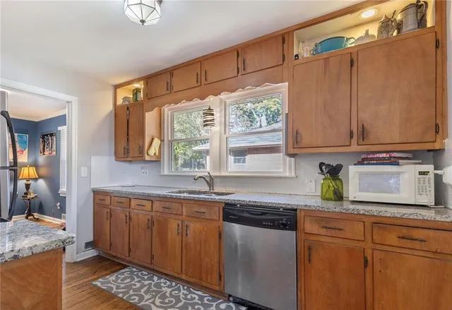 a kitchen with stainless steel appliances granite countertop a sink window and cabinets