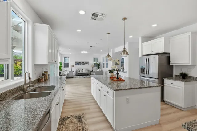 a kitchen with stainless steel appliances granite countertop a sink refrigerator and cabinets