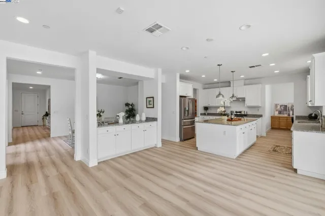 a view of kitchen with kitchen island sink refrigerator and white cabinets