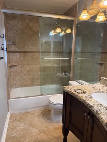 a bathroom with a granite countertop sink a toilet and shower