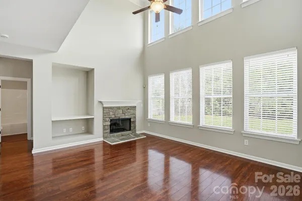 an empty room with wooden floor fireplace and windows