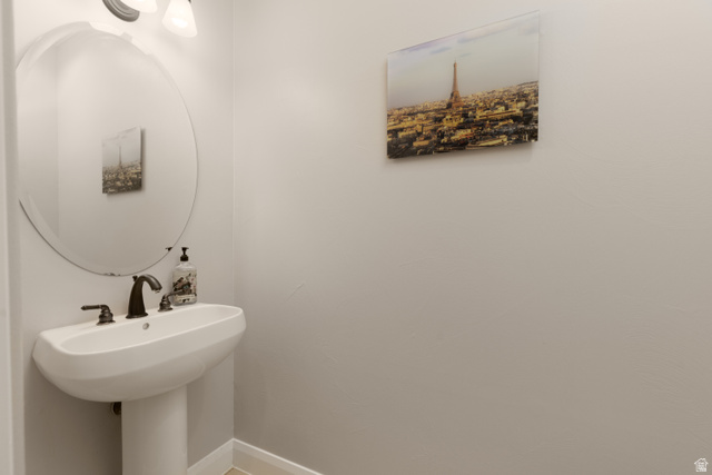 1257 West 2320 South St. George, UT 84770 - Photo 14 of 55 Pedestal sink with dark bronze faucet, oval mirror, and wall-mounted light fixture