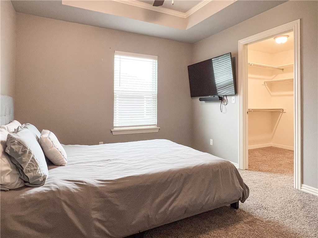 1275 North Rupple Road Fayetteville, AR 72704 - Photo 13 of 20 Carpeted room with tray ceiling, window with blinds, and a walk-in closet featuring built-in shelving
