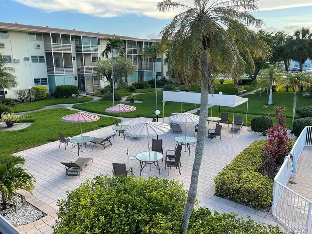 a view of a patio with table and chairs potted plants and palm trees