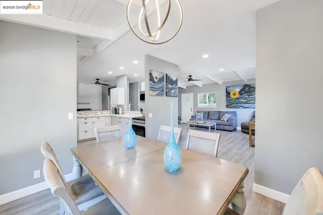 a dining room with kitchen island stainless steel appliances furniture dining table and wooden floor