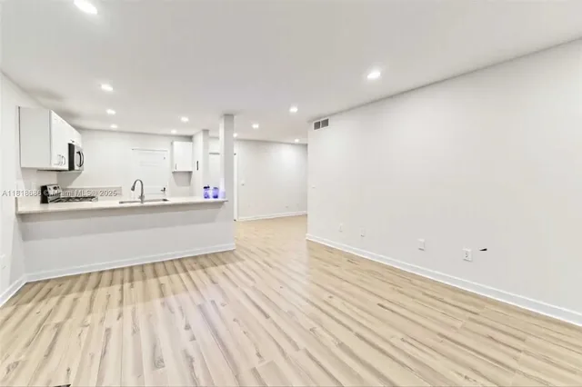 a kitchen with stainless steel appliances wooden floors and view living room