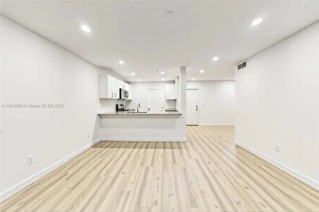 a view of kitchen with white wooden cabinets and stainless steel appliances