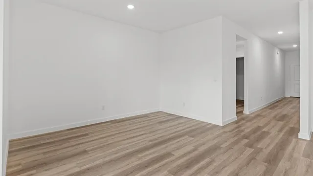 a view of an empty room with wooden floor and closet