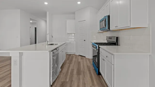 a kitchen with white cabinets sink and stove