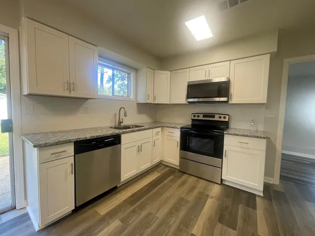 a view of kitchen with wooden floor electronic appliances and windows