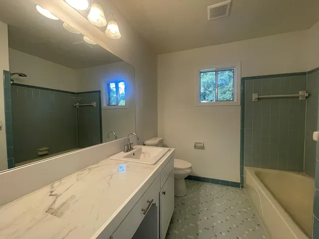 en empty room with windows and chandelier fan