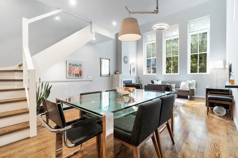 a dining room with wooden floor and large windows