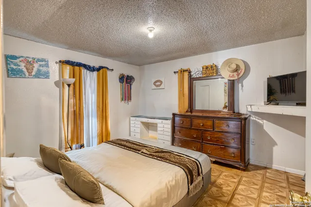 a bedroom with a bed and a flat tv screen on dresser