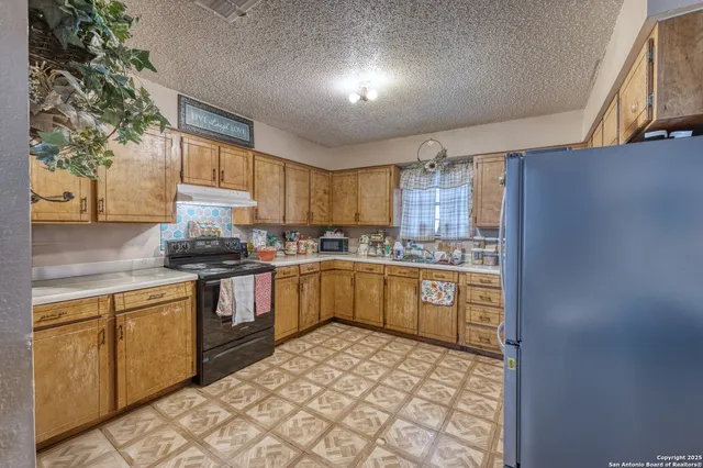 a kitchen with stainless steel appliances granite countertop a sink a stove a refrigerator cabinets and a window