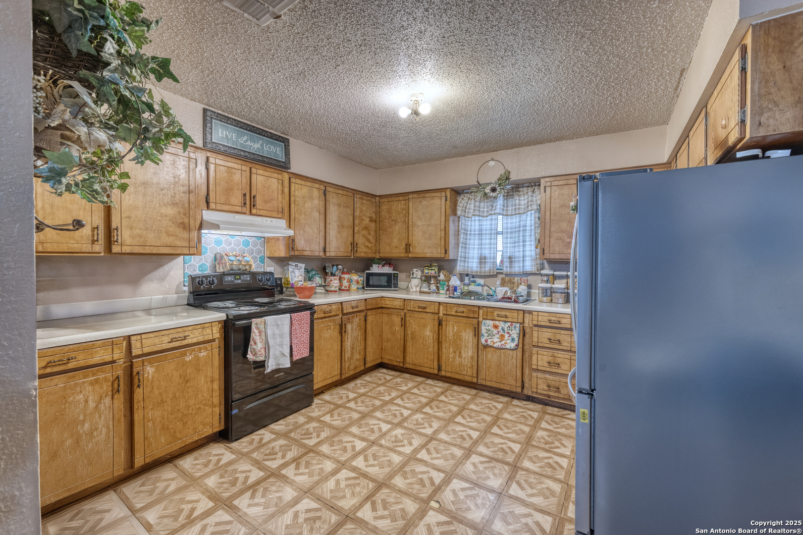 258 Prairie Street Uvalde, TX 78801 - Photo 5 of 19 a kitchen with stainless steel appliances granite countertop a sink a stove a refrigerator cabinets and a window