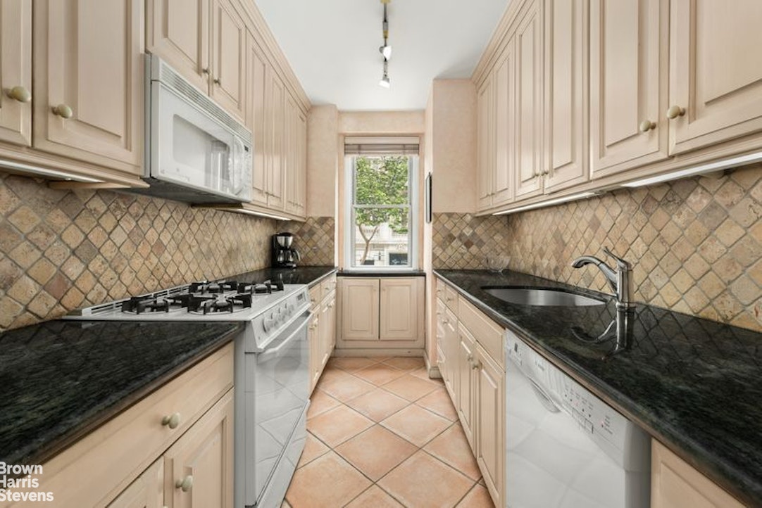 10 East 70th Street, Unit 2D Manhattan, NY 10021 - Photo 4 of 9 a kitchen with granite countertop white cabinets and appliances