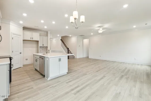a view of an empty room with wooden floor and a ceiling fan
