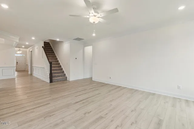 a view of an empty room with kitchen and a window