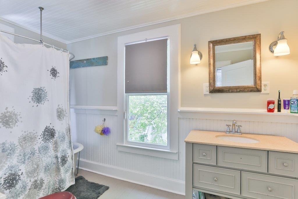 40 Abbott Street St. Augustine, FL 32084 - Photo 48 of 58 Bathroom featuring vanity, ornamental molding, a shower with shower curtain, and a wainscoted wall