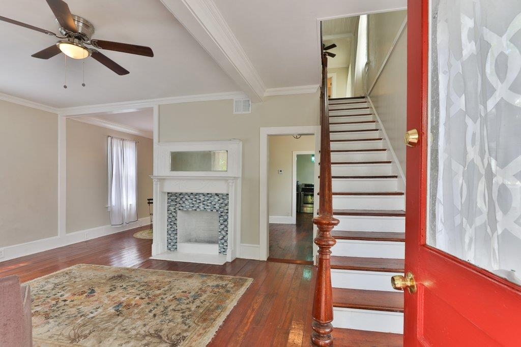 40 Abbott Street St. Augustine, FL 32084 - Photo 10 of 58 Staircase with wood-type flooring, crown molding, a fireplace, a ceiling fan, and beam ceiling