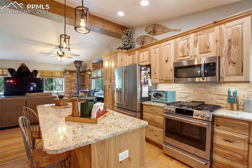 290 North Mountain Estates Road Florissant, CO 80816 - Photo 20 of 32 a kitchen with stainless steel appliances granite countertop a stove a refrigerator a dining table and chairs with wooden floor