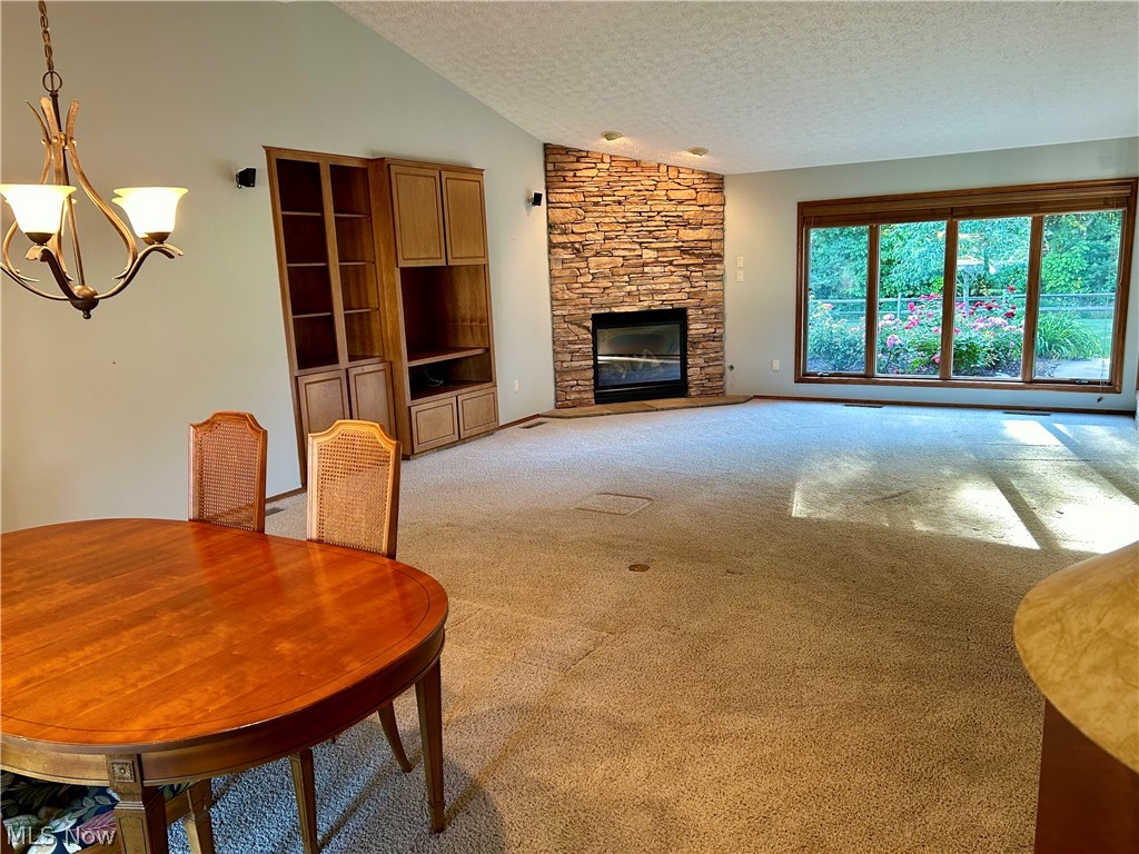 8763 Timber Edge Drive North Ridgeville, OH 44039 - Photo 15 of 40 Carpeted living room featuring a textured ceiling, a notable chandelier, vaulted ceiling, and a fireplace