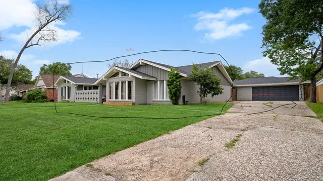 a view of a white house in front of a big yard with large trees