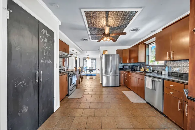 a kitchen with stainless steel appliances granite countertop a refrigerator and a view of living room