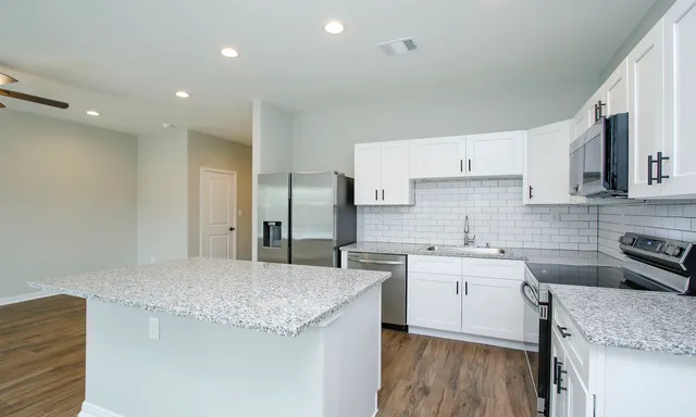 a kitchen with stainless steel appliances granite countertop a stove a sink and a refrigerator