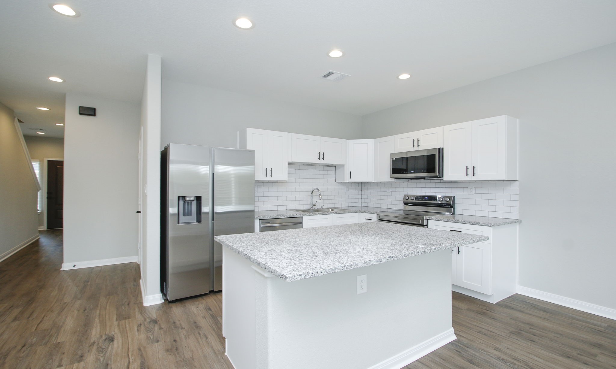 14010 Longstreet Road, Unit 9 Willis, TX 77318 - Photo 21 of 50 a kitchen with stainless steel appliances white cabinets a sink a stove a microwave and wooden floor