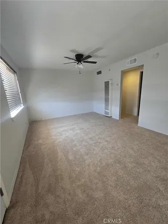 an empty room with a chandelier fan and windows
