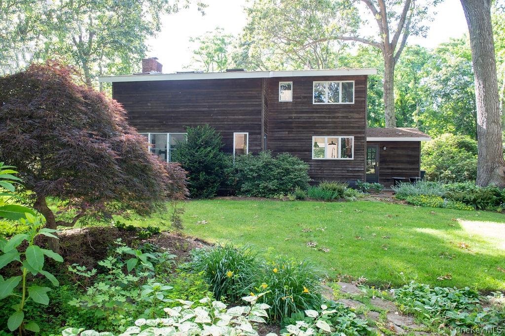 1045 Wagon Wheel Lane Cutchogue, NY 11935 - Photo 2 of 31 a view of a brick house with a small yard plants and large trees